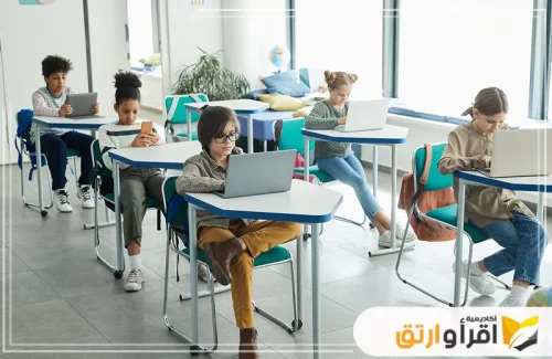 طلاباً متنوعين من حيث الأعمار والأعراق يجلسون في قاعة دراسية ويستخدمون التكنولوجيا في التعليم، مما يدل على اعتماد التعليم في المدارس على التقنيات الحديثة