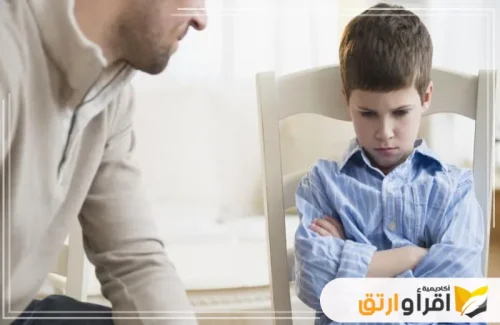 طفلاً يجلس معقود الذراعين وعبوسًا، بينما يكلمه شخص بالغ. تعكس هذه اللقطة تحديات غرس القيم والأخلاق، حيث يتطلب الأمر صبرًا وتفهمًا من الأهل لتوجيه الأطفال نحو السلوكيات الصحيحة