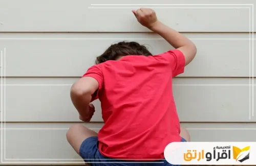 يظهر طفل يرتدي قميصًا أحمر وهو يواجه الحائط بوضعية تعكس الشعور بالإحباط. تعكس الصورة مشهدًا يحتاج إلى تدخل التربية الأخلاقية للأطفال