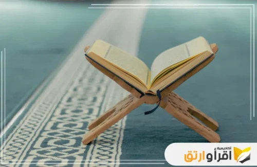 مصحف شريف مفتوح على حامل خشبي، مع خلفية من السجادة الزرقاء المزخرفة. يُمكن ربط هذه الصورة بحلقات قرآن أونلاين