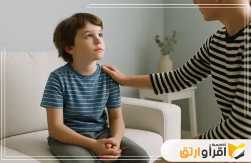 امرأة تضع يدها على كتف طفل، تنظر إليه وتتحدث معه باهتمام. تعكس هذه اللقطة أهمية التخاطب وتعديل السلوك، حيث يساعد التواصل المباشر بين الأهل والطفل على بناء الثقة