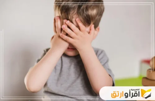 طفلاً يغطي وجهه بيديه، مما يعكس شعورًا بالخجل أو الانزعاج أو صعوبة في التعبير عن نفسه. هذه المشاعر قد تكون مؤشرًا على تحديات في التواصل تستدعي تدخل دكتور تخاطب