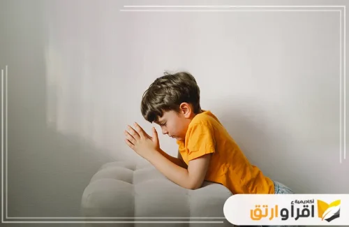 طفلًا صغيرًا وهو يجلس على الأريكة، ممسكًا يديه معًا في وضع يشير إلى التركيز العميق. يعكس هذا المشهد شعورًا بالهدوء علاج القلق والخوف.