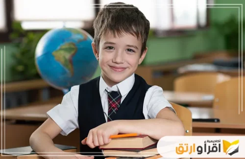 طفلاً يرتدي زيًا مدرسيًا ويجلس على مكتب، وابتسامته الواثقة توحي بالتقدم والنجاح. تعكس هذه الصورة أهمية علاج صعوبات التعلم، حيث يمكن أن تساعد الجلسات التعليمية الفردية الطلاب