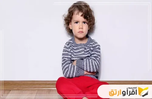 طفلاً يجلس على الأرض وهو عابس وذراعاه متقاطعتان، مما يعكس شعورًا بالغضب أو الرفض. تُبرز هذه اللقطة أهمية غرس القيم والأخلاق من سن مبكرة، حيث يحتاج الأطفال إلى التوجيه المستمر